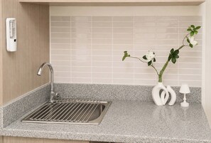 A kitchen with a stainless steel sink, a water filtration system, and a vase with flowers. - The Sky Nook Cubao Near Gateway & MRT (Quezon City)