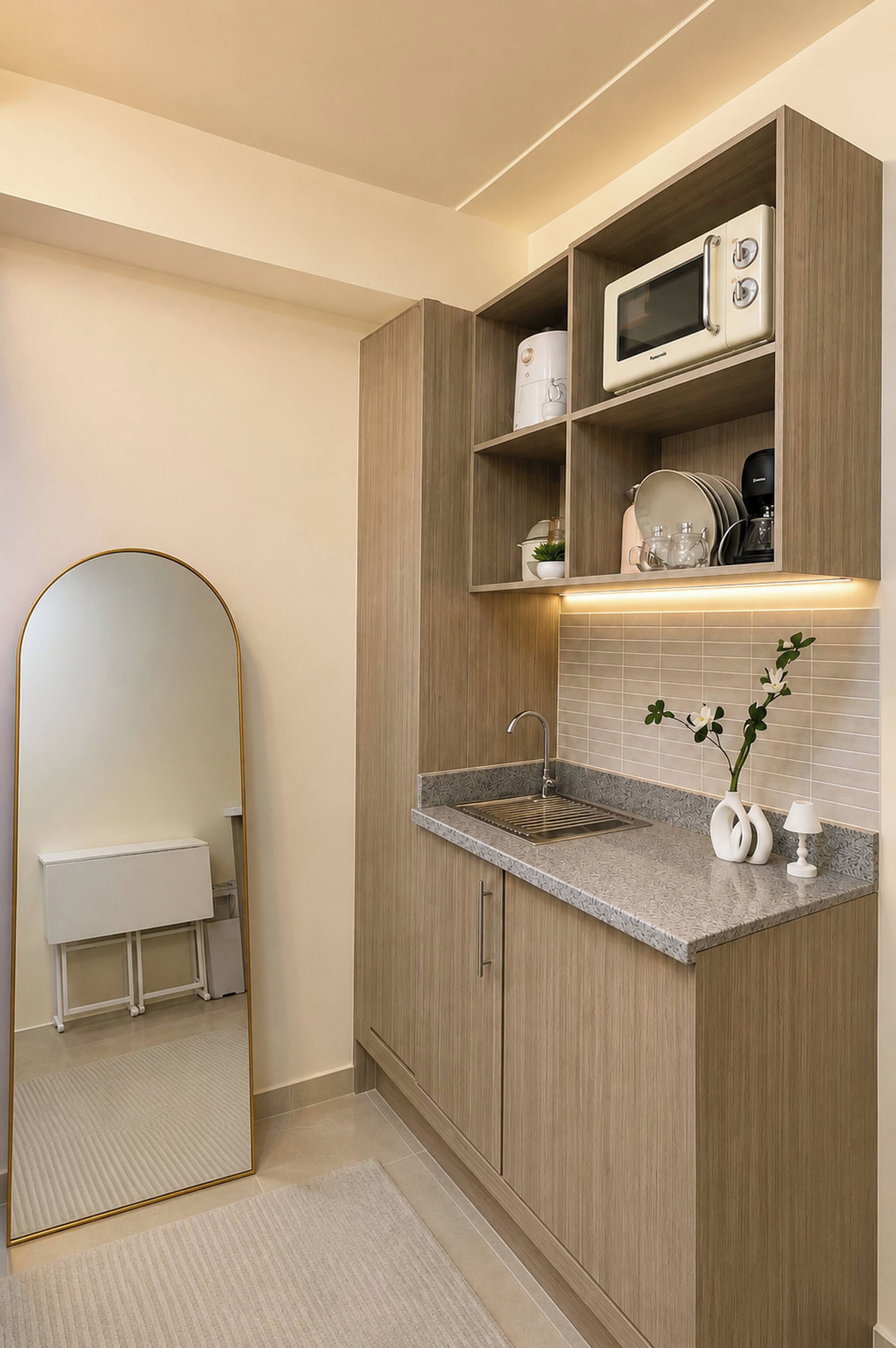 A modern kitchen with a built-in microwave, a sink, and a mirror.