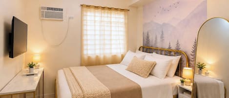 Quarto de hotel com cama, mesas de cabeceira, televisão, janela com cortinas e um mural na parede.
