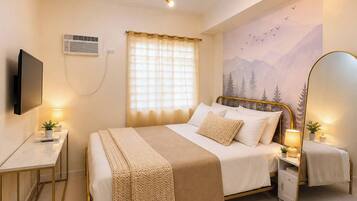 A hotel room with a bed, bedside tables, a TV, a window with curtains, and a wall mural.