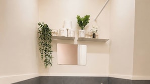 A modern bathroom with a toilet, a sink, and a mirror. There are toiletries on a shelf and a plant hanging on the wall. - The Sky Nook Cubao Near Gateway & MRT (Quezon City)