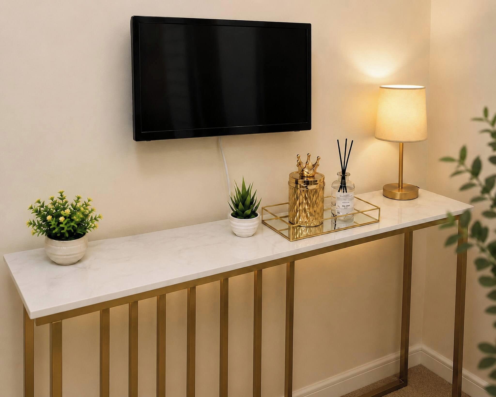 A reception desk with a flat-screen TV mounted above it, a table lamp, and decorative items including a small plant and a gold-colored decorative piece.
