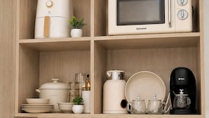 A kitchen with a microwave, coffee maker, and various kitchenware on shelves. - The Sky Nook Cubao Near Gateway & MRT (Quezon City)