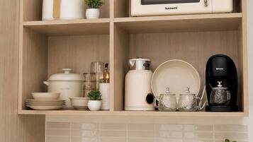A kitchen with a microwave, coffee maker, and various kitchenware on shelves.