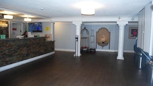 A reception area with a stone counter, a television screen, and a wheelchair-accessible ramp. - Heritage Inn and Suits (San Bernardino)