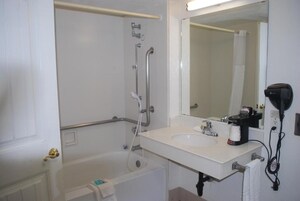 A bathroom with a bathtub, a sink, a mirror, and a hairdryer.