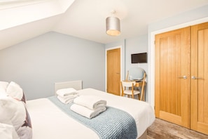 A bedroom with a bed, a desk, a chair, a television, and a wardrobe. - 4 Brindles Manse - North East Escapes (North Sunderland)