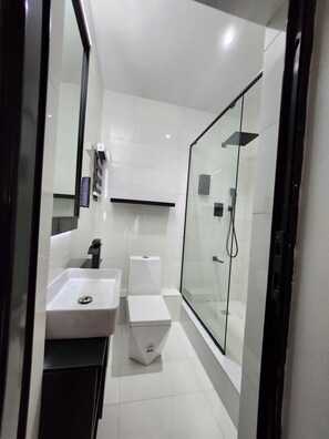 A modern bathroom with a glass-enclosed shower, a white sink, and a toilet. - Crib 14 (Lagos)