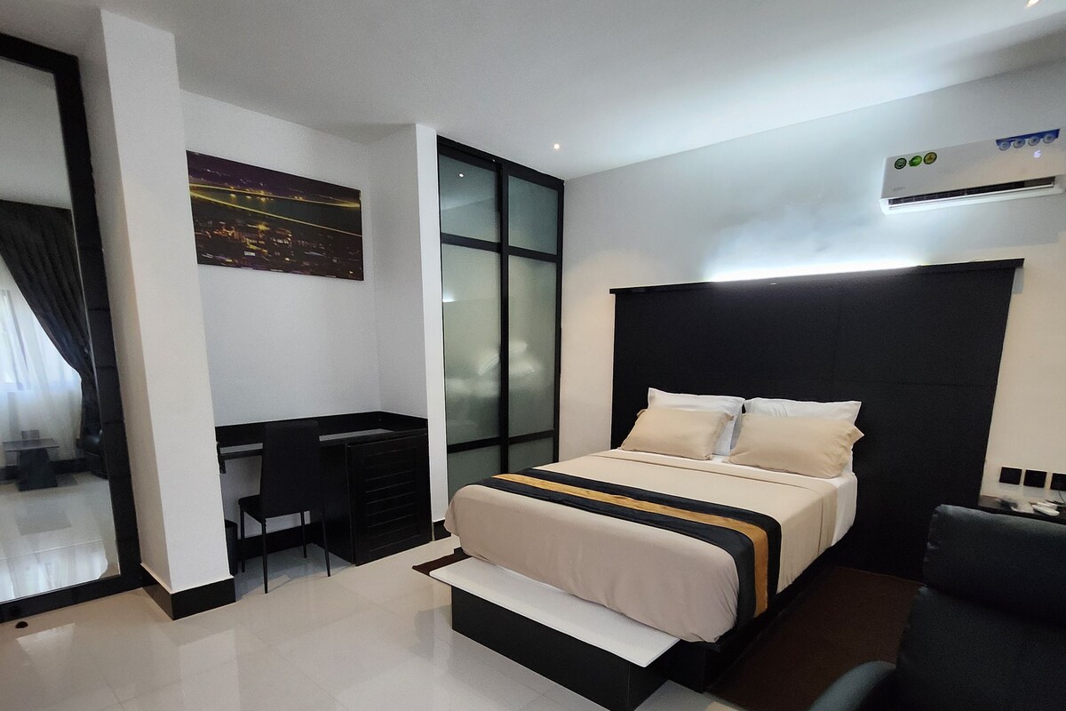 A modern hotel room with a bed, a desk, and a chair.