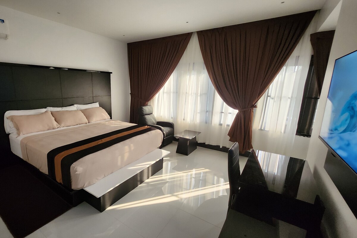 A modern hotel room with a large bed, a flat-screen TV, and a desk.