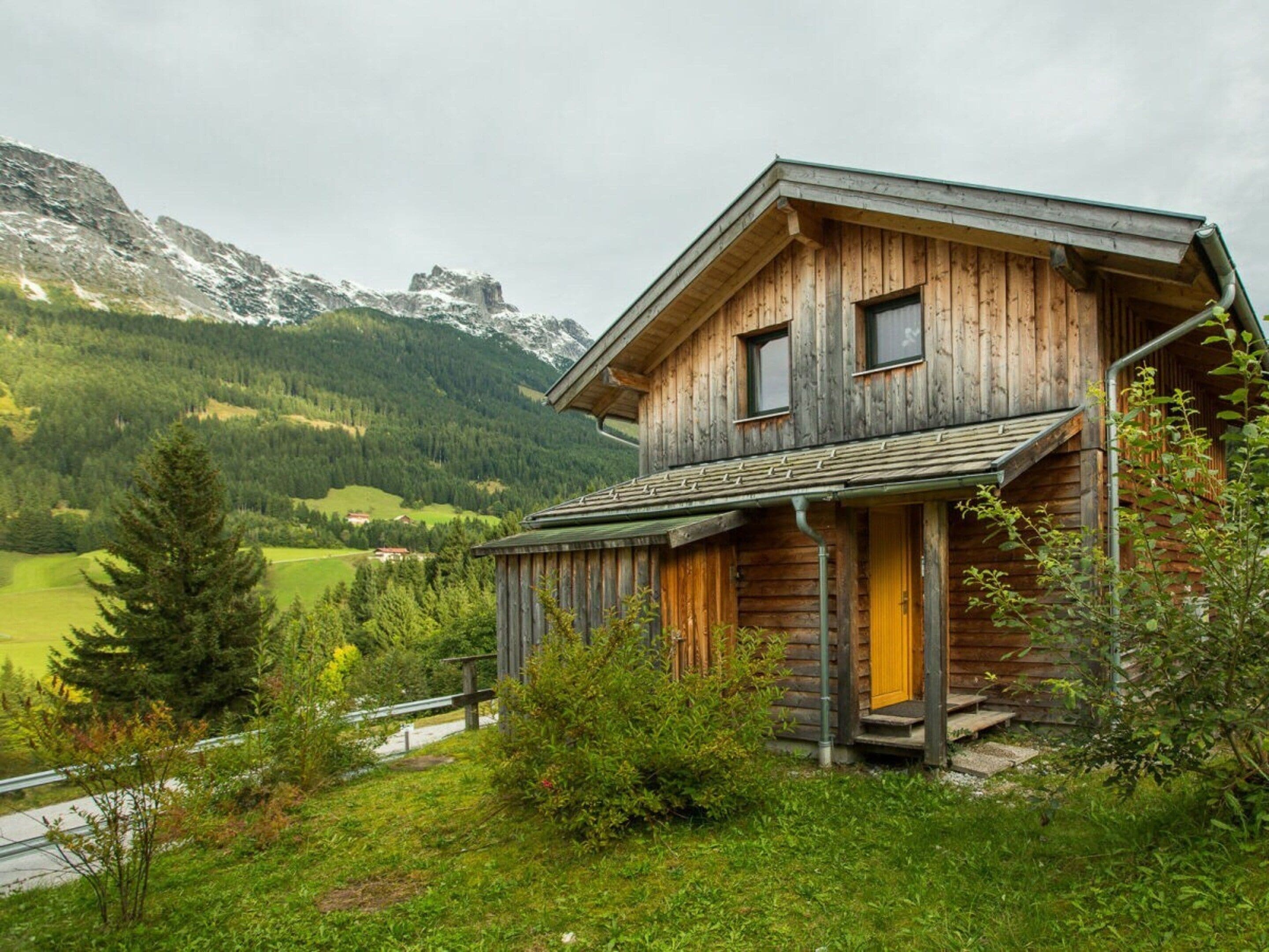 Eine Holzhütte mit geneigtem Dach, einer Veranda und Blick auf eine gebirgige Landschaft.