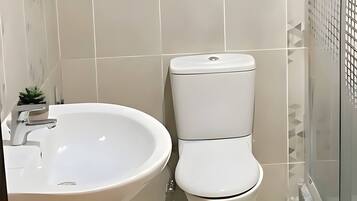 A bathroom with a white sink, toilet, and a glass shower enclosure.