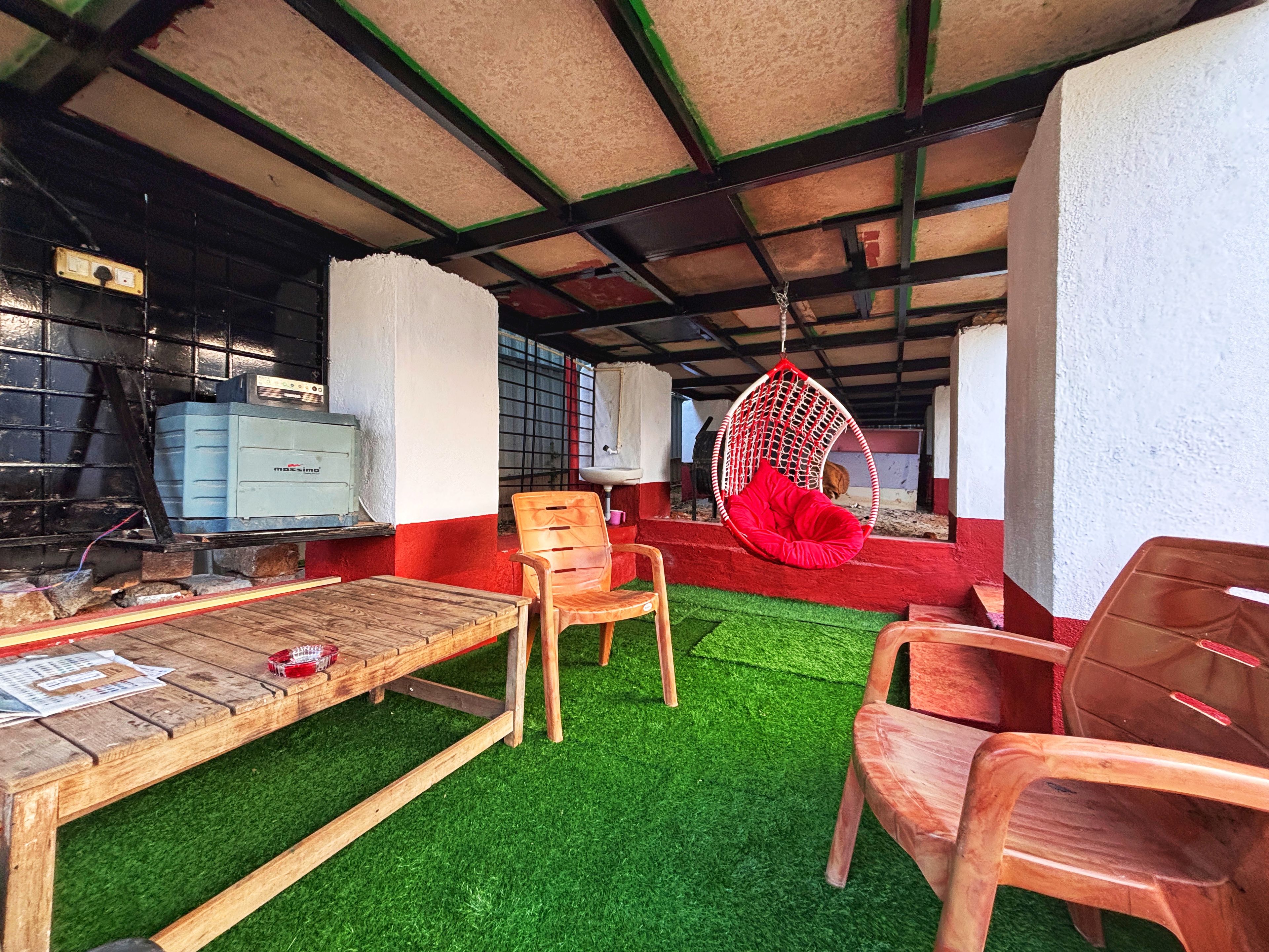 Una habitación con una mesa de madera, sillas, un sillón colgante y un sofá pequeño.