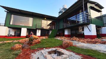 A two-story building with a green and white facade, a visible staircase, and a small garden area with rocks and gravel.