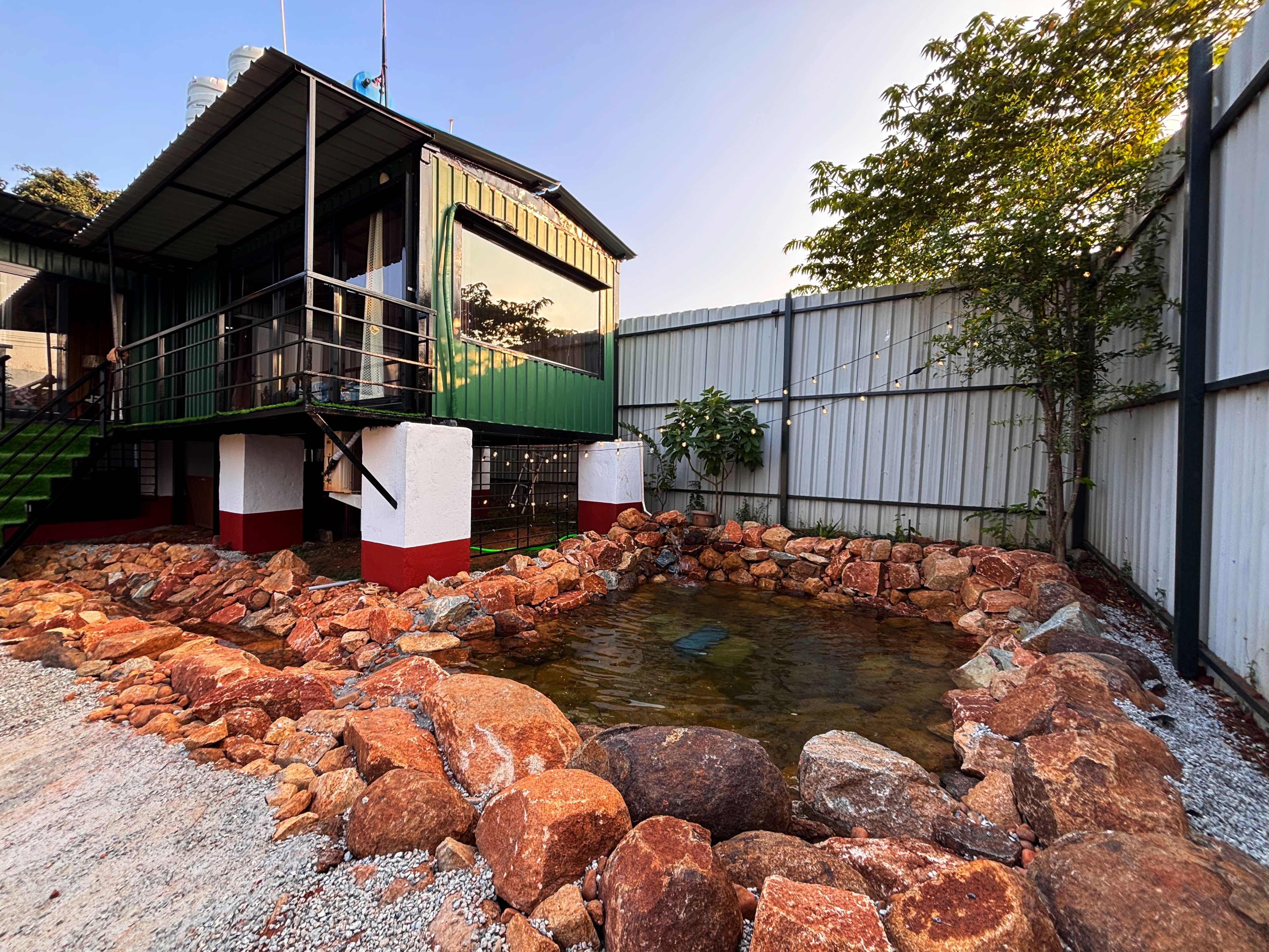 A building with a green and white exterior, a stone water feature, and a metal fence.