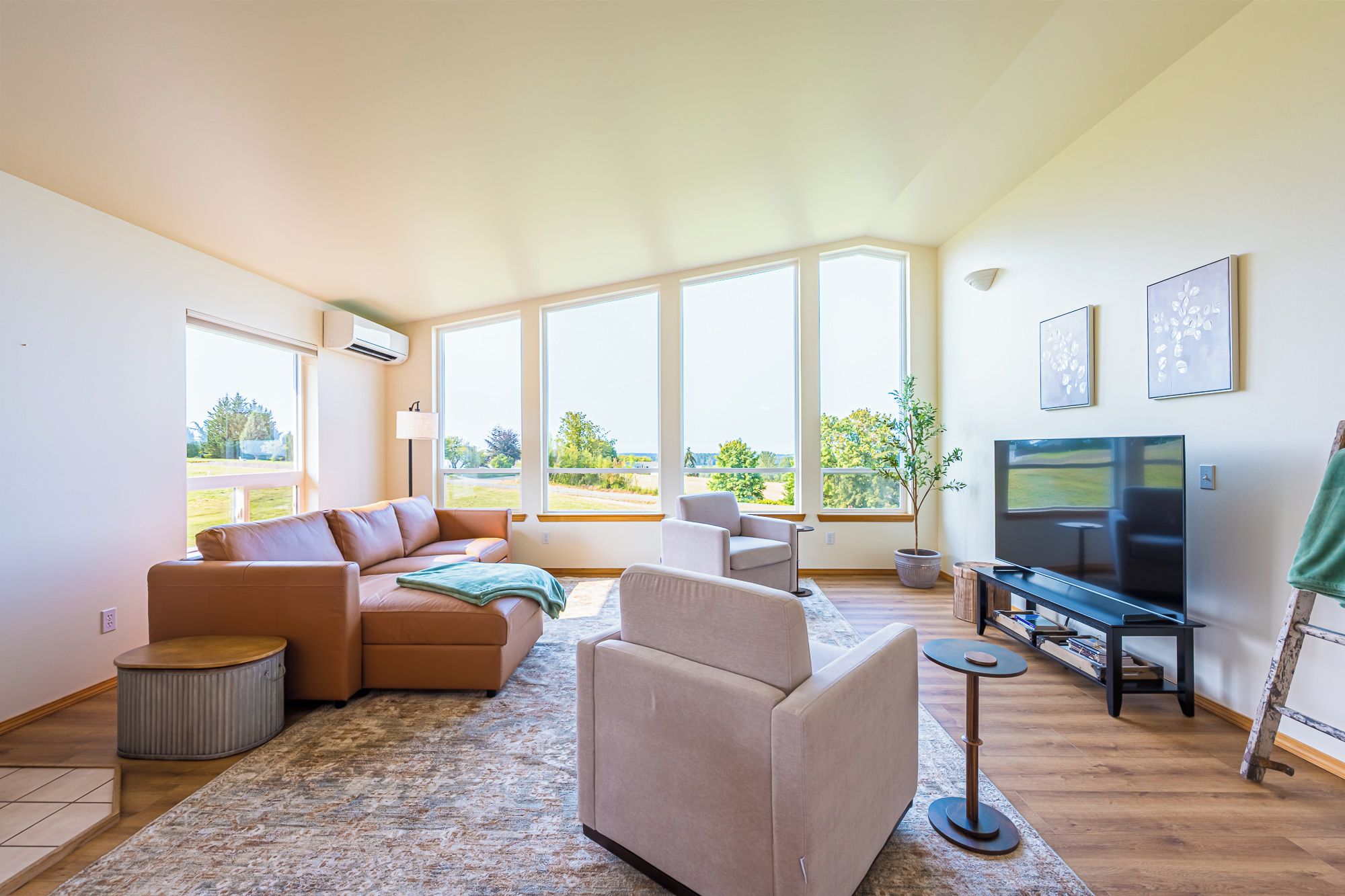 Ein großzügiger Wohnraum mit einem großen Fenster, einem Sofa, einem Couchtisch und einem Fernseher.