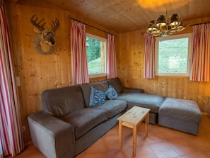 A wooden cabin interior with a sofa, a small table, and a deer head mounted on the wall. - Cabin in Annaberg With Swimming Pool (Annaberg-Lungoetz)