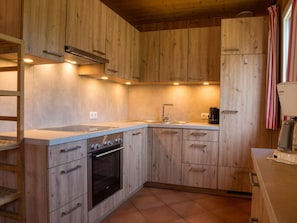 A compact kitchen with wooden cabinets, a built-in oven, and a coffee maker. - Cabin in Annaberg With Swimming Pool (Annaberg-Lungoetz)
