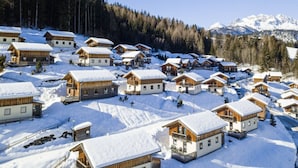 Un pueblo cubierto de nieve con edificios de madera, cielo despejado y una montaña al fondo.
