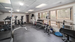 Une salle de sport équipée de divers appareils d’exercice, notamment des tapis de course, des appareils de musculation et des poids libres.