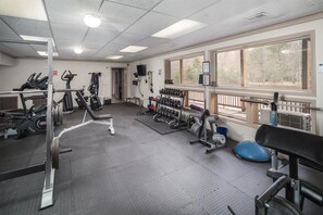 A gym with various exercise equipment, including treadmills, weight machines, and free weights.