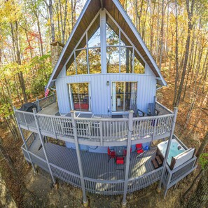 A cabin with a balcony, a hot tub, and a deck.