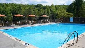 Une piscine avec un panneau indiquant qu’il est interdit de plonger, entourée de chaises longues et de parasols.