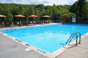 A swimming pool with a no diving sign, surrounded by lounge chairs and umbrellas.