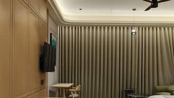 Quarto de hotel moderno com cama, escrivaninha, cadeira, televisão e ventilador de teto.