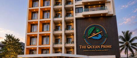 A multi-story hotel with a prominent logo, balconies, and a well-lit entrance.