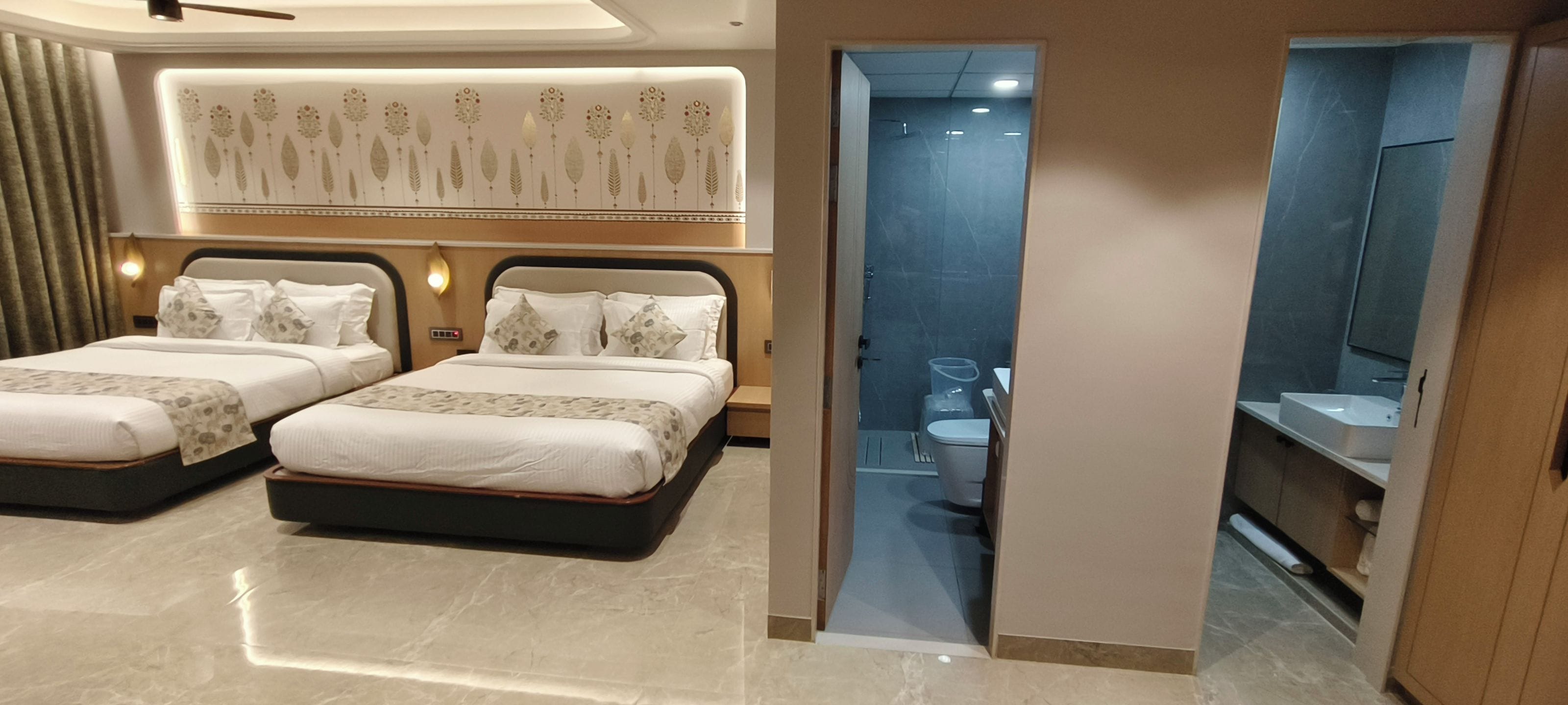 A hotel room with two beds, a bathroom, and a mirror.