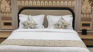 A large bed with a dark headboard, white linens, and decorative pillows.