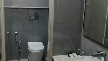 Un baño moderno con ducha de vidrio, inodoro blanco y un espejo grande.