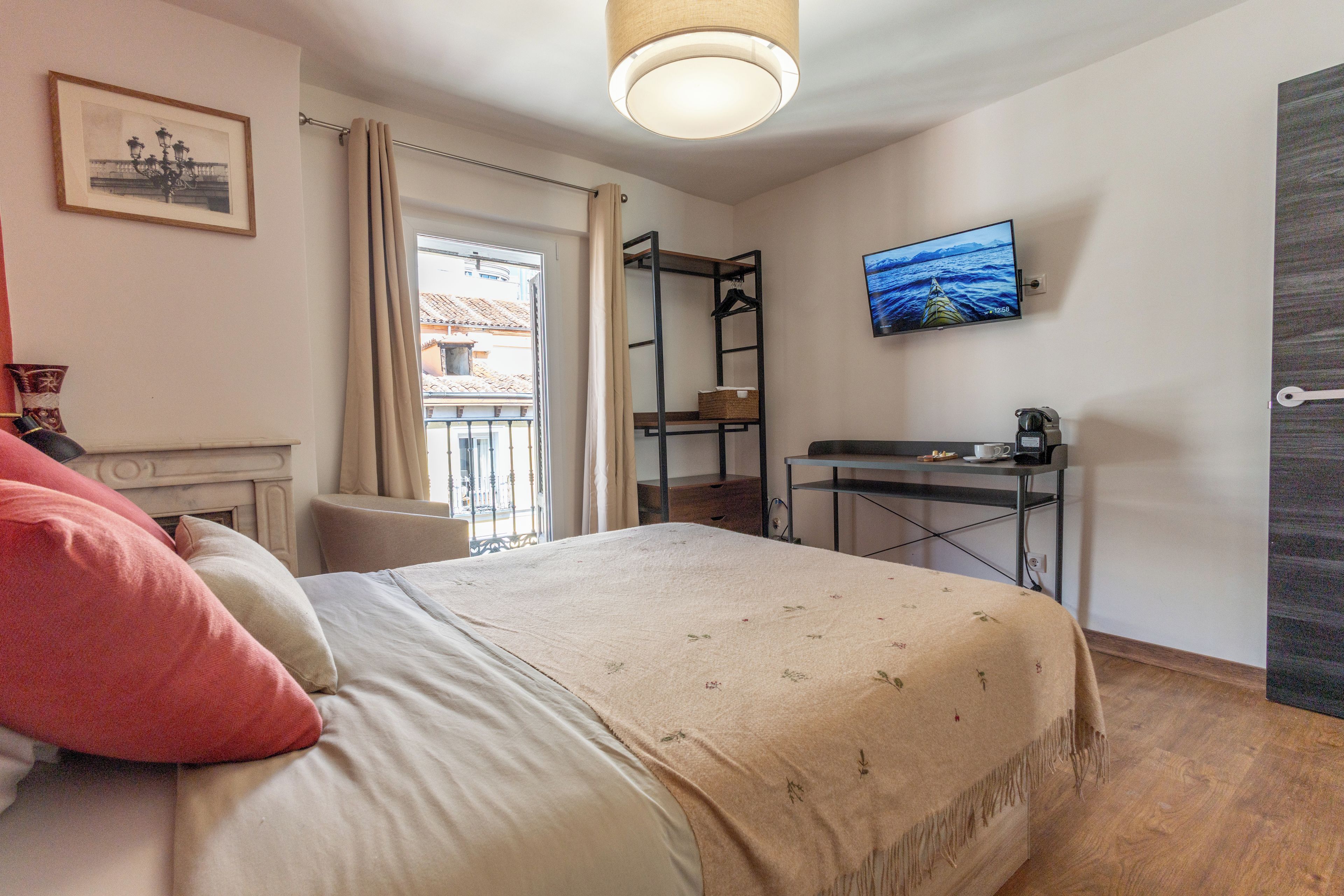 Un dormitorio con cama, escritorio, televisor y ventana con cortinas.