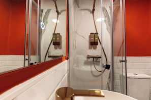 A bathroom with a glass-enclosed shower, a white sink, and a mirror.