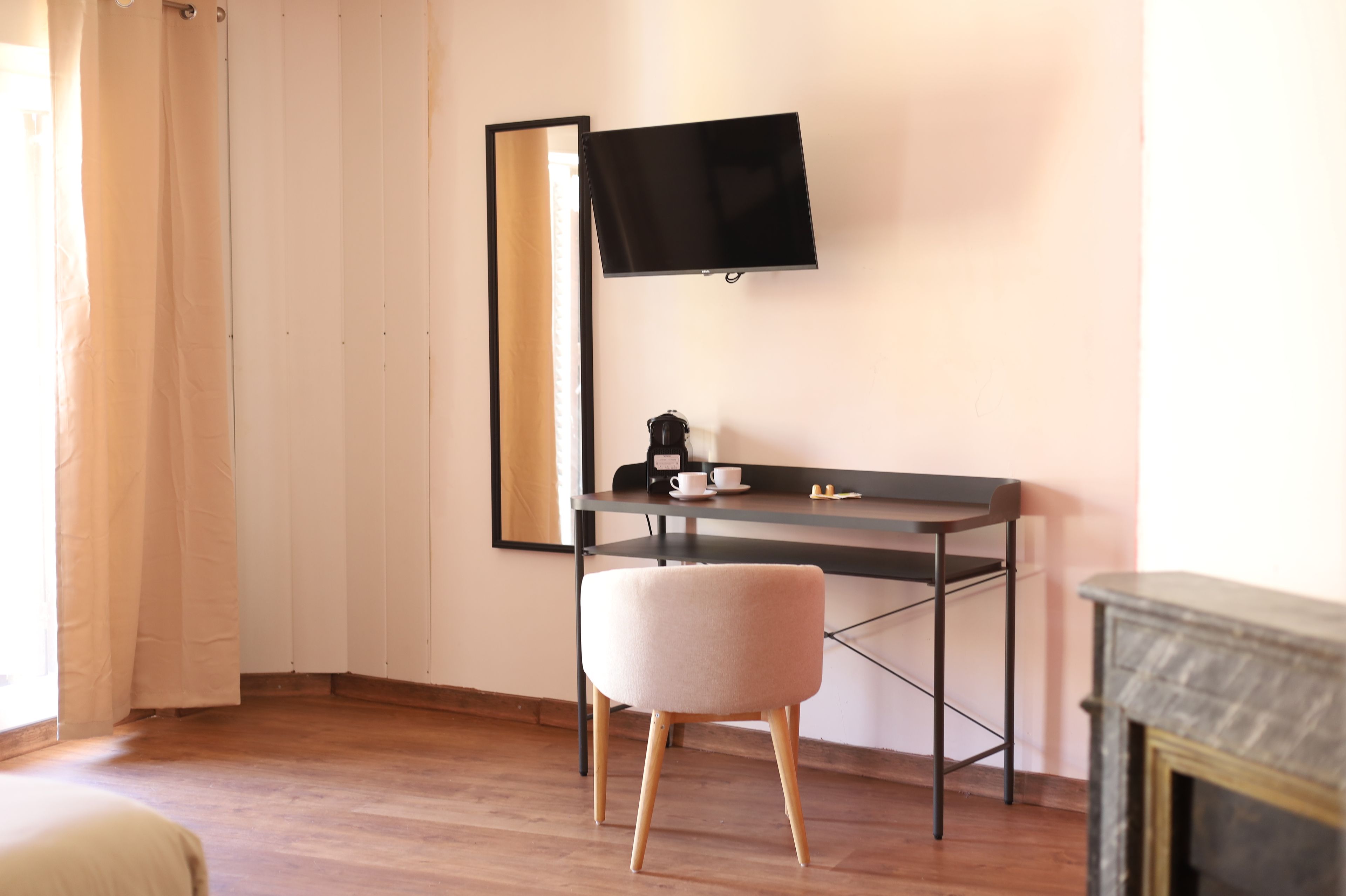 Une chambre moderne avec un plancher en bois, un bureau doté d’un téléviseur à écran plat, une chaise et une cheminée.
