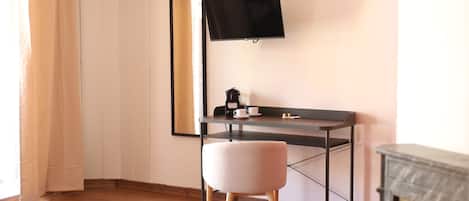 Una habitación moderna con piso de madera, un escritorio con televisor de pantalla plana, una silla y una chimenea.