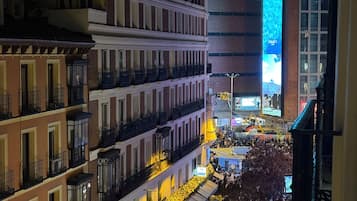 Un paisaje urbano nocturno con edificios, una pantalla iluminada grande y una multitud.