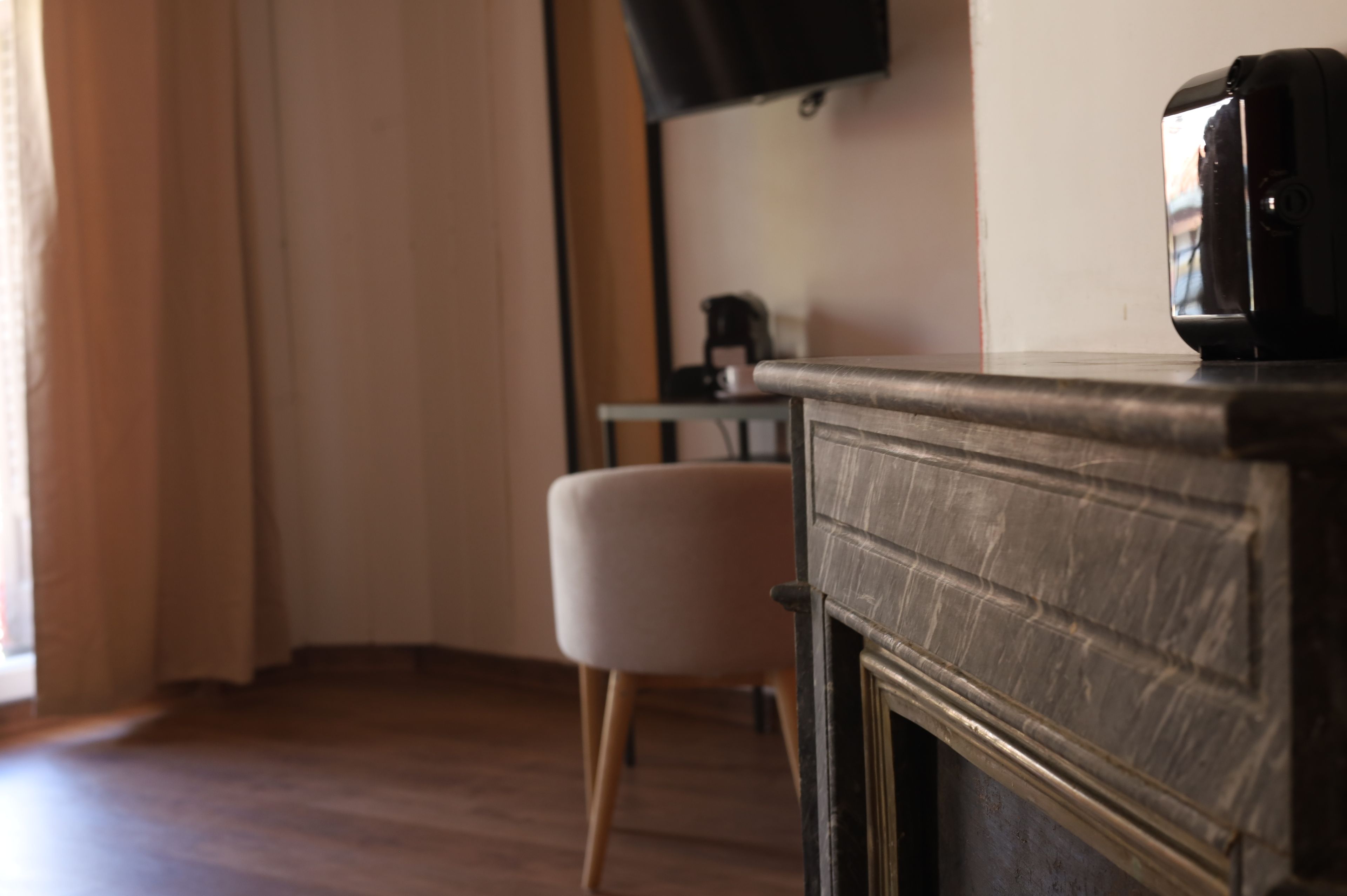 Ein Zimmer mit einem Holzkabinett, einem an der Wand befestigten Fernseher und einem Sessel.