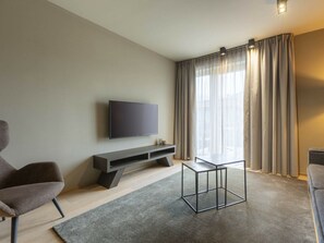 Un salon moderne avec un téléviseur à écran plat fixé au mur, une table basse au design épuré et un canapé confortable.