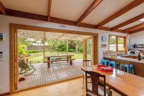 A kitchen with a wooden table, blue bar stools, and a view of the backyard.