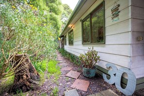 Una casa amb un camí que condueix a l'entrada, envoltada de vegetació i un gran rètol amb el número 30.