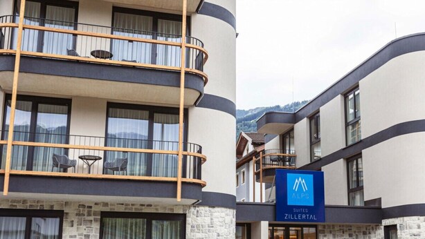 Um hotel com design moderno, com varandas e área de estar externa, e uma placa com o nome 'Zillertal'.