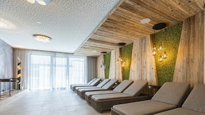 Um espaço de spa com uma fileira de espreguiçadeiras, teto de madeira e parede verde.