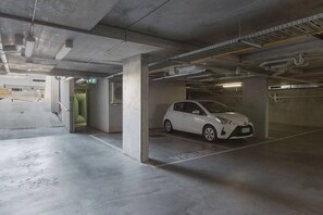 Un estacionamiento con un coche blanco aparcado en zona de visitantes.