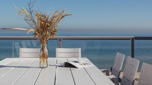 Una mesa con un jarrón de plantas secas, un menú y vista al mar.