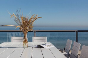 A table with a vase of dried plants, a menu, and a view of the sea. - Bonbeach Bliss Contemporary Waterfront Living (Bonbeach)