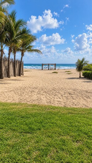 A beach with a wooden gazebo, palm trees, and a clear blue sky. - Casa Serena (Santa María Colotepec)
