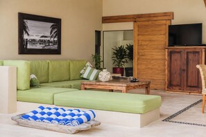A living room with a green sofa, a coffee table, a television, and a wooden cabinet. - Casa Serena (Santa María Colotepec)
