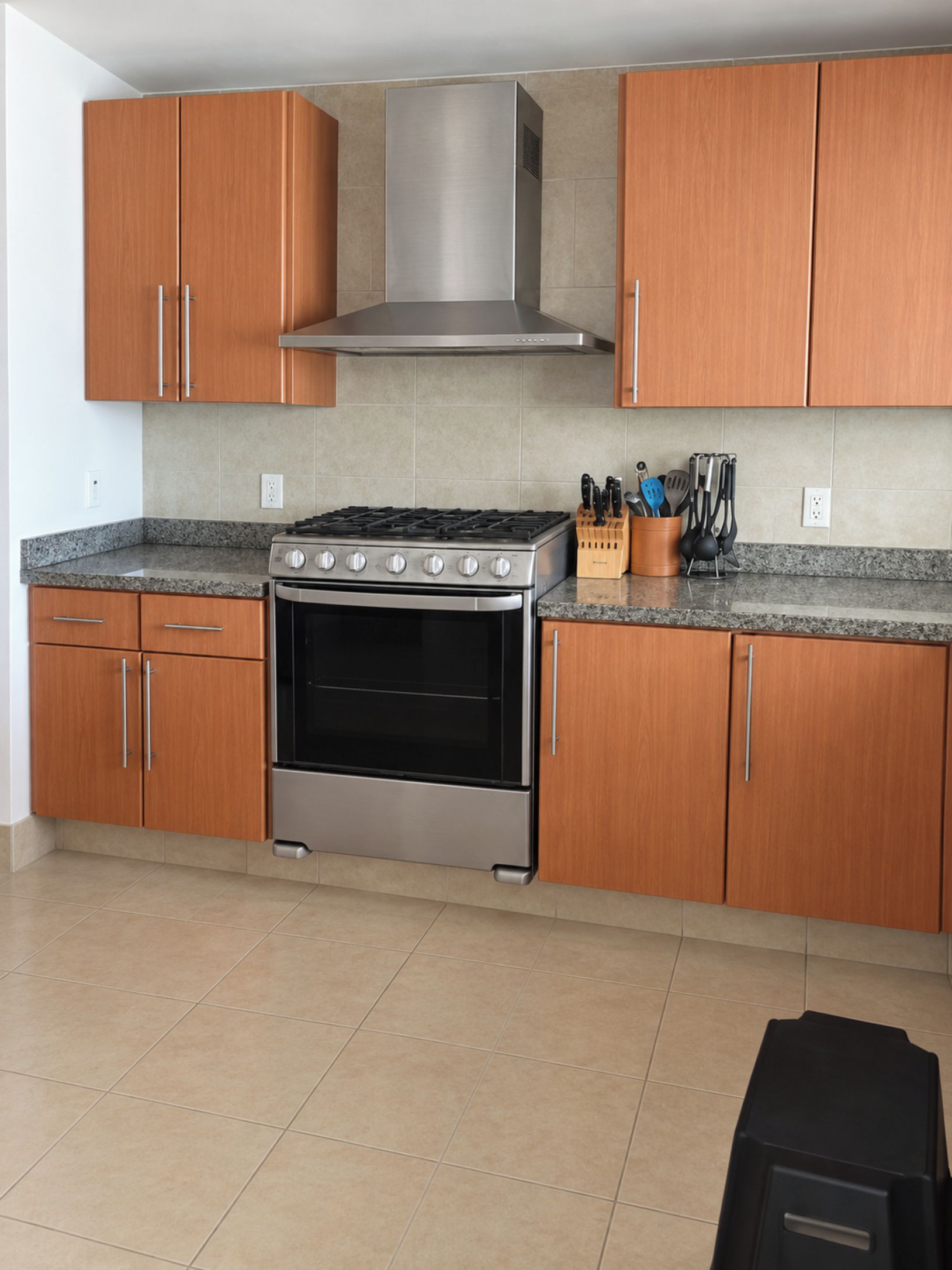 A kitchen with wooden cabinets, a stainless steel range hood, a gas stove, and a built-in oven.
